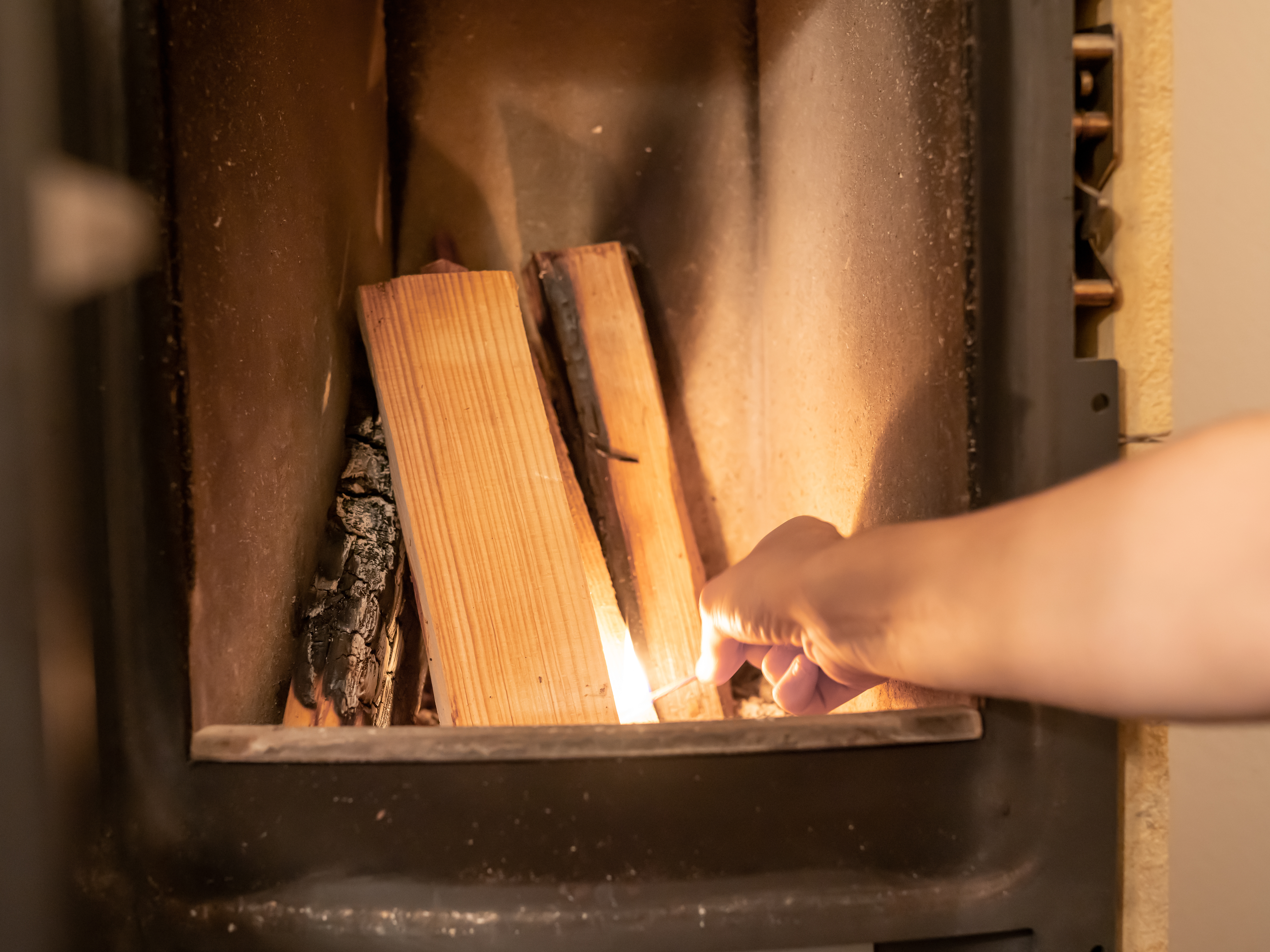 Effektives Anzünden des Kamins Hand zündet Holz im Kamin an